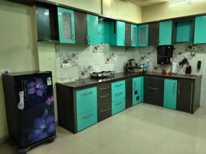 a kitchen with blue cabinets and a refrigerator at Avs Jain's house in Ujjain