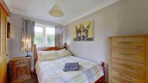 a bedroom with a bed and a dresser and a window at F72 Chyreden, Riviere Towans in Hayle