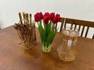 a table with red tulips in a vase on a table at Homestay Bunga Raya Wifi Netflix in Sitiawan