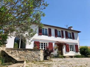 a house with red shutters and a stone wall at L'adret du bois in Sames