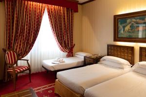 a hotel room with two beds and a chair at Grand Hotel Trento in Trento