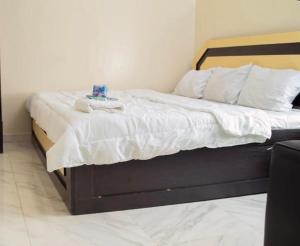 a bed with a wooden frame and white sheets and pillows at Jiksonodohotel in Nsukka
