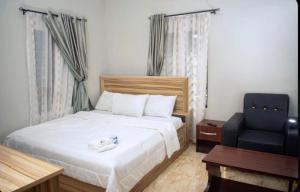 a bedroom with a bed and a blue chair at Jiksonodohotel in Nsukka