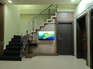 a lobby with a staircase with a television on the wall at Avs Jain's house in Ujjain