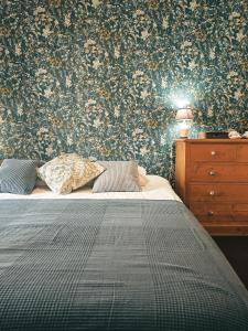a bedroom with a bed and a wall with floral wallpaper at Auberge de Chanteuges in Chanteuges