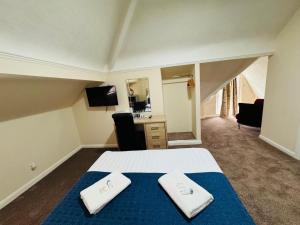a bedroom with a bed with two towels on it at Trivelles Belforte Hotel , Sale, Manchester - M33 2AE in Sale