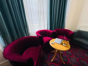 a room with red chairs and a table with a laptop at Trivelles Belforte Hotel , Sale, Manchester - M33 2AE in Sale