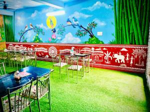 a room with tables and chairs and a mural at MAHAMAYA CONVENTION and HOTEL in Mālatīpātpur