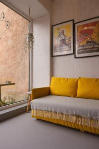 a living room with a yellow couch and a window at Liepaja Garden Studio with Terrace in Liepāja