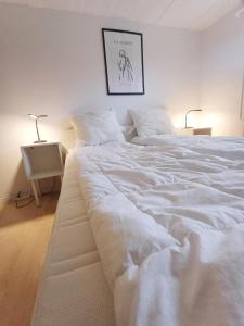 a large white bed in a bedroom with a picture on the wall at Central apartment in Aalborg close to Hospital in Aalborg
