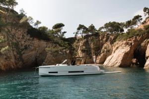 a white boat in the water next to a cliff at Finca Victoria, a Member of Design Hotels in Begur
