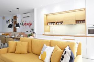 a living room with a yellow couch and a kitchen at Mariposa in Marbella