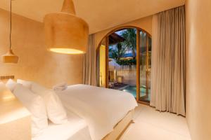 a bedroom with a white bed and a large window at La Isla Boutique Residences in Uluwatu +39 photos