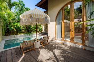 a patio with two chairs and an umbrella next to a pool at La Isla Boutique Residences in Uluwatu