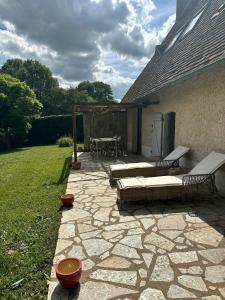 a patio with a table and benches on a yard at Charming cottage in Boursay +18 photos