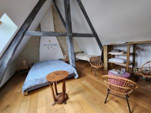 a bedroom with a bed and chairs in a attic at Charming cottage in Boursay
