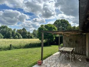 a picnic table on a patio with a view of a field at Charming cottage in Boursay