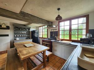 a large kitchen with a wooden table in it at Charming cottage in Boursay