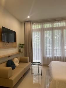 a living room with a couch and a tv on the wall at The Highland House in Buon Ma Thuot