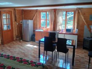a kitchen with a table and chairs and a refrigerator at Cabañas CyG 2 - Chaitén in Chaitén