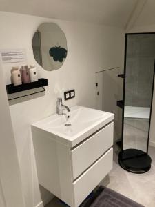 a white bathroom with a sink and a mirror at Christina in Nieuwpoort +24 photos