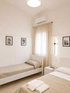 a white bedroom with two beds and a window at Casa Corallium in Torre del Greco