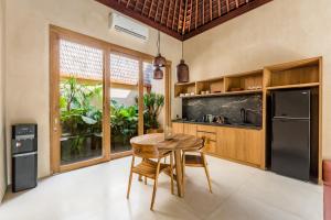 a kitchen with a wooden table and a refrigerator at La Isla Boutique Residences in Uluwatu