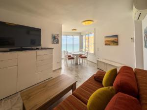 a living room with a couch and a flat screen tv at Increíbles vistas al mar A102 in Torrox Costa