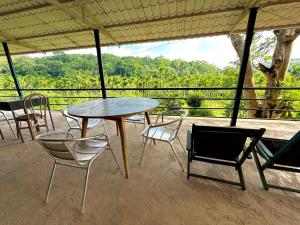a table and chairs on a porch with a view at Whispering Willows in Gūdalūr