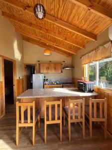 a kitchen with a table and some chairs and a refrigerator at Cabañas Lago Huillinco in Chonchi