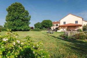 a large yard with a house and a tree at Les Tilleuls de Marie in Saint-Edmond