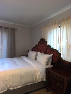 a bedroom with a large bed with a wooden headboard at Siyapeya Household in Bellville