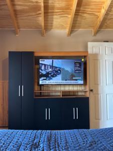 a bedroom with a flat screen tv and a bed at Cabañas Lago Huillinco in Chonchi