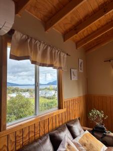a living room with a couch and a large window at Cabañas Lago Huillinco in Chonchi