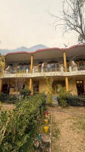 a large yellow building with a balcony on top of it at Parma Guest House in Kasol