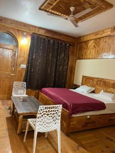 a bedroom with a bed and a table and chairs at Parma Guest House in Kasol