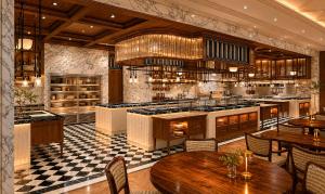 ein Restaurant mit Tischen und einer Küche mit Herd in der Unterkunft Marqen Hotel in Jakarta