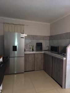 a kitchen with a stainless steel refrigerator and wooden cabinets at Siyapeya Household in Bellville