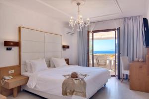 ein Schlafzimmer mit einem großen weißen Bett und einem Kronleuchter in der Unterkunft Valtos Beach Hotel in Parga + 195 Fotos