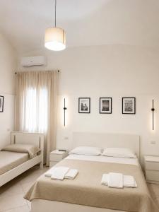 a white bedroom with two beds and a window at Casa Corallium in Torre del Greco