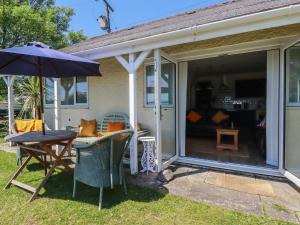 a screened in porch with a table and an umbrella at Rollies Retreat in Fowey