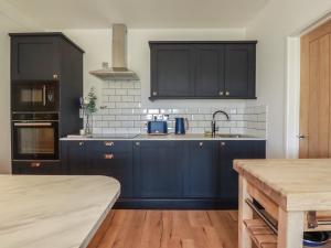 a kitchen with dark blue cabinets and a sink at Rollies Retreat in Fowey