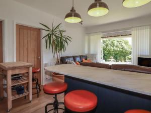 a living room with a bar with red stools at Rollies Retreat in Fowey