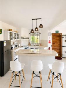 a kitchen with white chairs and a large island at Pointe D'Esny Villa 1 in Mahébourg +14 photos