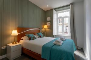 a bedroom with a bed with a blue blanket and a window at Lisbon Poets Inn in Lisbon