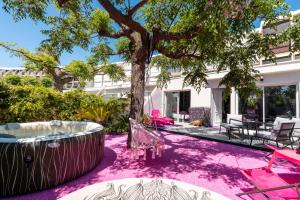 a pink carpeted yard with a tree and a hot tub at Villa L'Hyliadenna avec jardin - parking privé - au cœur du Village Naturiste, NaturaBeach Héliopolis - Plage à pied in Cap d'Agde