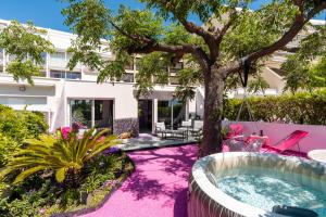 an exterior view of a building with a hot tub and a tree at Villa L'Hyliadenna avec jardin - parking privé - au cœur du Village Naturiste, NaturaBeach Héliopolis - Plage à pied in Cap d'Agde