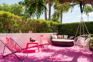 a patio with pink chairs and a swing at Villa L'Hyliadenna avec jardin - parking privé - au cœur du Village Naturiste, NaturaBeach Héliopolis - Plage à pied in Cap d'Agde