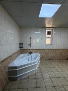 a large bath tub in a bathroom with a window at Iman Guest House in Al Qurayyah