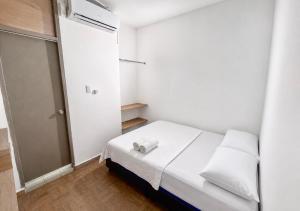 a small white room with a bed and a door at Ocean Blue Centro Histórico Hotel in Santa Marta